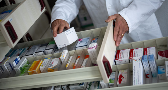 Ein Apotheker holt eine Medikamentenverpackung aus einer Schublade in einer Apotheke.