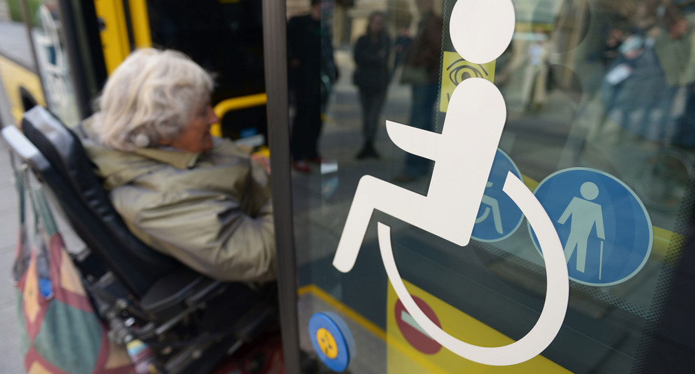 Eine Rollstuhlfahrerin fährt über eine spezielle Rampe in einen Stadtbus (Bild: © dpa).