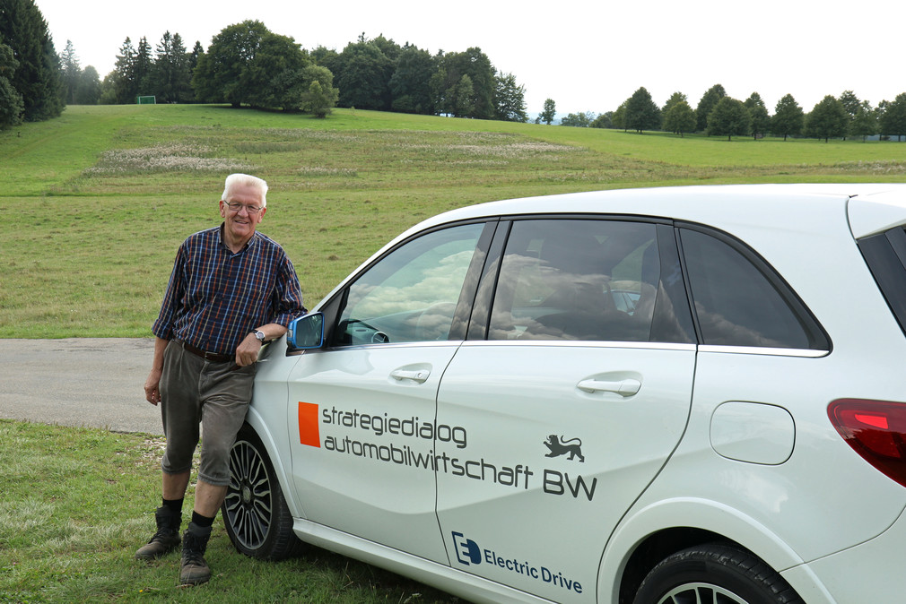 Ministerpräsident Winfried Kretschmann neben einem Elektrofahrzeug, mit dem er die Fahrstrecken zwischen den einzelnen Etappen zurücklegt