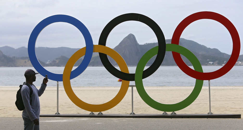 Ein Mann fotografiert die olympischen Ringe in Rio de Janeiro (Quelle: dpa).