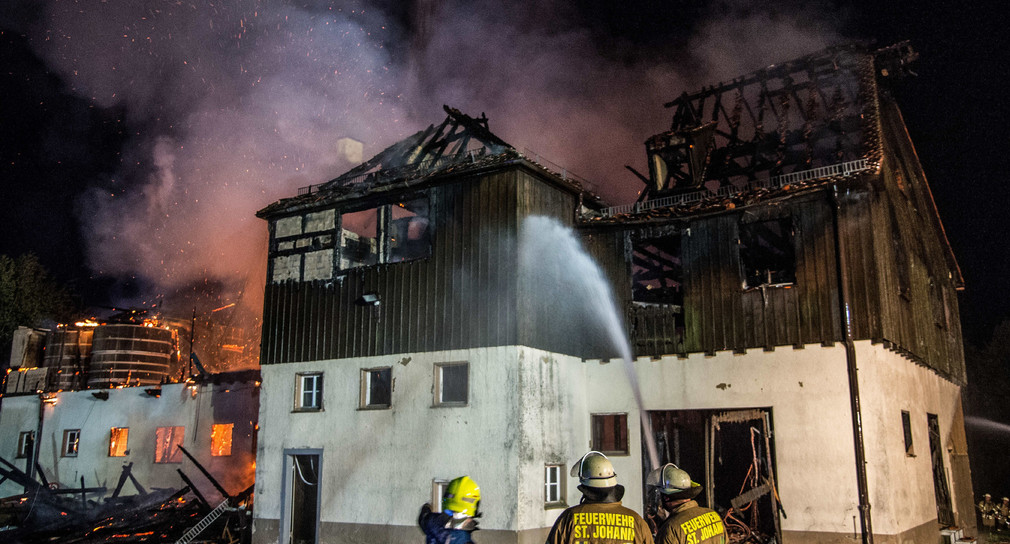 Drei Feuerwehrmänner löschen die Flammen, die in der Nacht zum 16. August 2017 aus einem Gebäude des Gestütshofs St. Johann schlagen. (Foto: dpa)