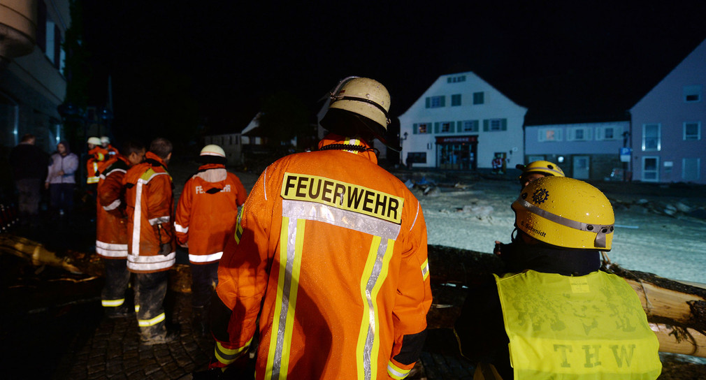 Feuerwehrleute stehen in der Ortsmitte von Braunsbach (Baden-Württemberg). Durch heftigen Regen sind zwei kleine Bäche über die Ufer getreten, Häuser und Autos wurden beschädigt (Quelle: dpa).
