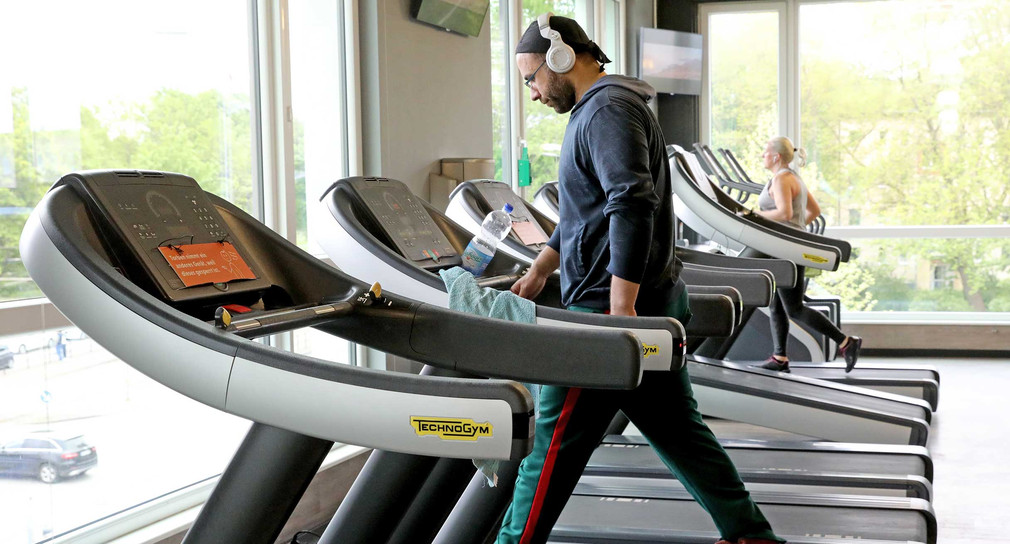 Ein Mann trainiert auf einem Laufband in einem Fitnessstudio.