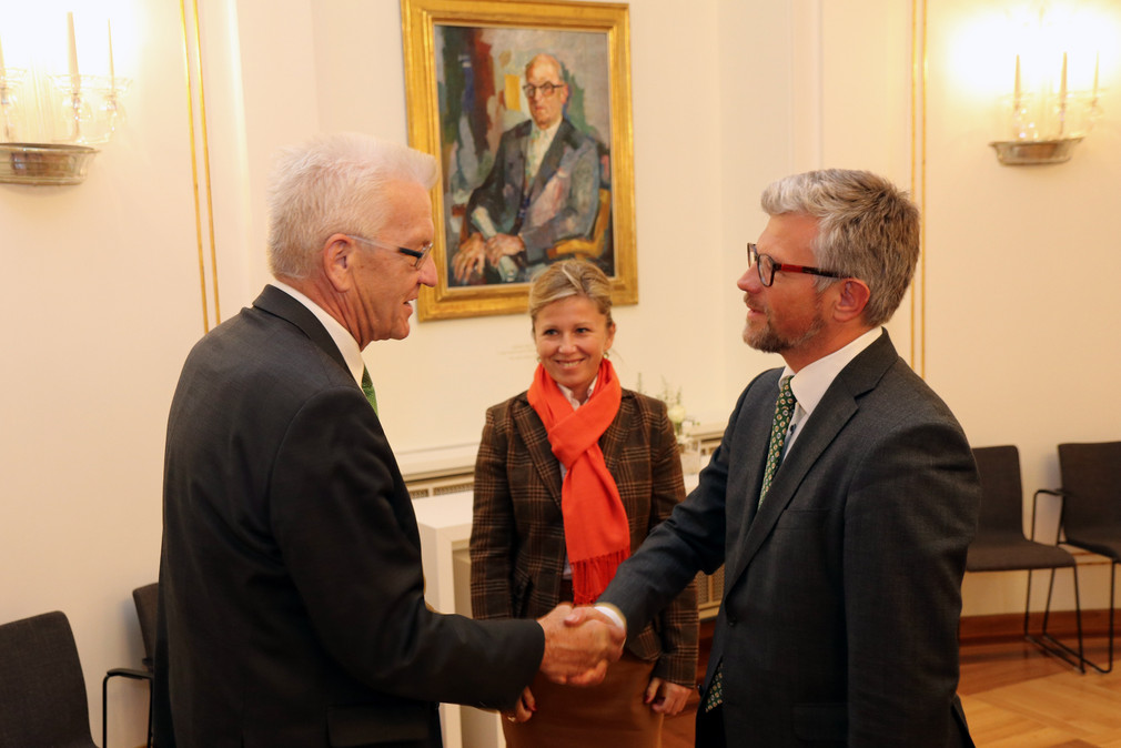Ministerpräsident Winfried Kretschmann (l.) begrüßt den ukrainischen Botschafter Andrij Melnyk (r.) und dessen Ehefrau (M.)