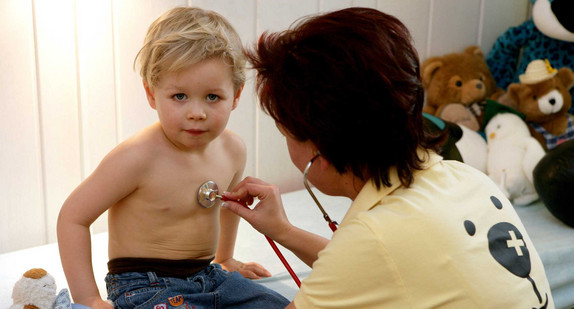 Eine Kinderärztin untersucht einen kleinen Jungen mit einem Stethoskop (Bild: © dpa). 