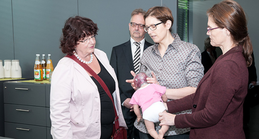 Dr. Christina Jaki (M.) erläutert Staatssekretärin Bärbl Mielich (l.), was bei einem Schütteltrauma im Gehirn eines Babys passiert. (Foto: Techniker Krankenkasse)