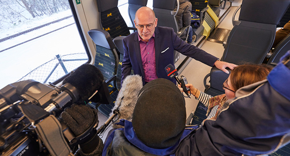 Verkehrsminister Winfried Hermann spricht während einer Zugfahrt mit der Presse. (Foto: © Ministerium für Verkehr / Beaufort 8 GmbH)