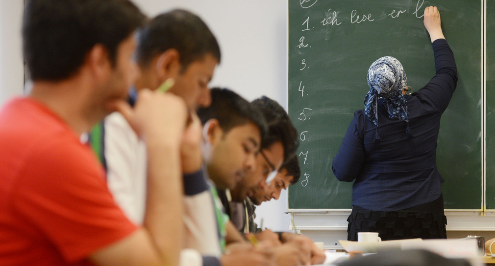 Eine Schülerin schreibt in Schwäbisch Gmünd beim Deutschunterricht für Asylbewerber auf die Tafel (Bild: © Franziska Kraufmann/dpa).