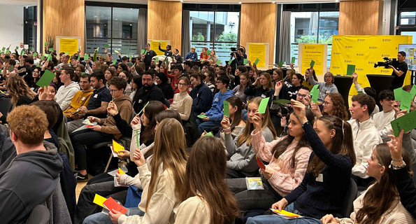 Jugendliche mit Abstimmungskarten in einem Saal