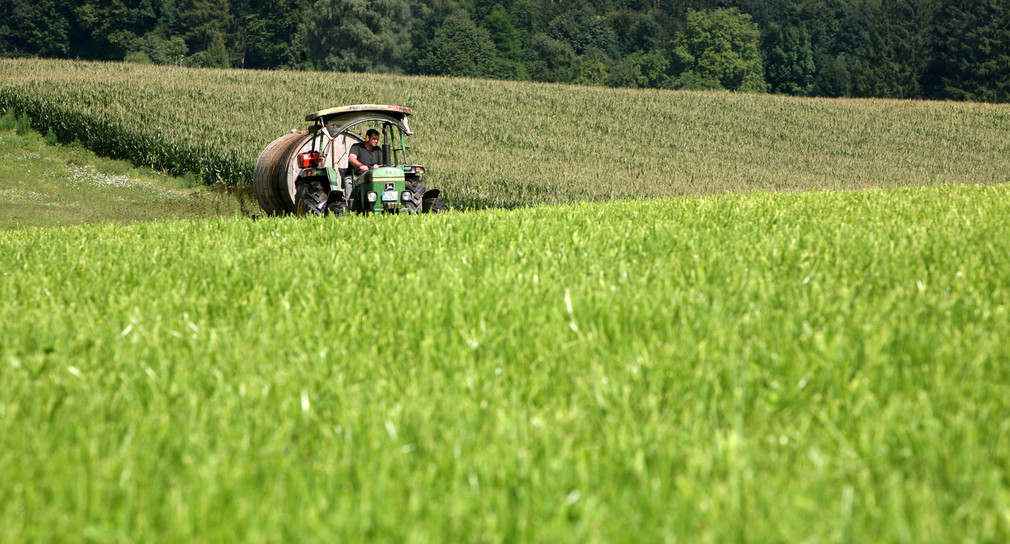 Ein Bio-Bauer bringt mit seinem Traktor und einem Tankwagen als Anhänger, die angefallende Jauche auf einer Wiese aus. (Bild: dpa)