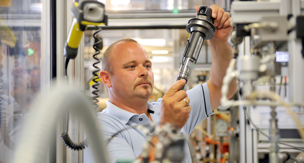 Ein Arbeiter in der Produktion prüft ein Bauteil. (Foto: © Bosch)