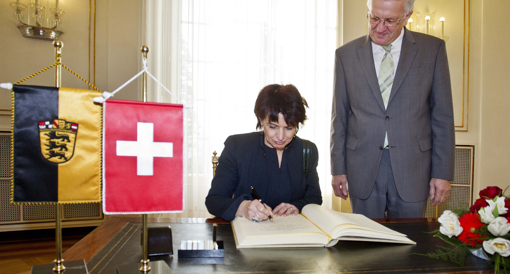 Die Schweizer Bundesrätin Doris Leuthard (l.) trägt sich im Beisein von Ministerpräsident Winfried Kretschmann (r.) in das Gästebuch des Landes ein.