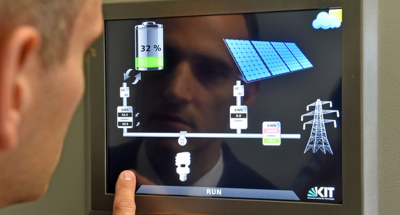Eine Person steht an einer Systemstatusanzeige eines Solarstrom-Speicher-Parks.