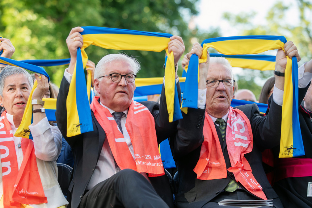 von links nach rechts: Irme Stetter-Karp, Präsidentin des Zentralkomitees der deutschen Katholiken (ZdK), Bundespräsident Frank-Walter Steinmeier und Ministerpräsident Winfried Kretschmann halten bei der Eröffnung des Katholikentags gelb-blaue Schals in den Händen.