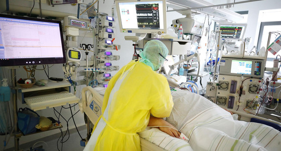 Ein Arzt untersucht einen Patienten auf einer COVID-19 Intensivstation.
