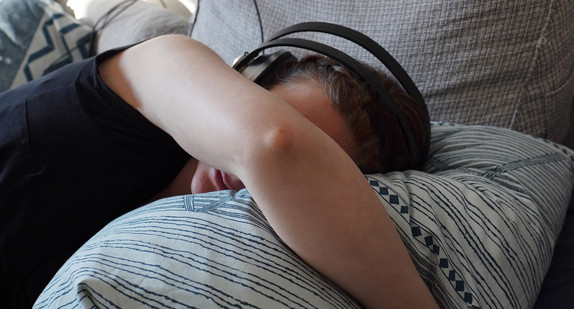 Eine Frau liegt auf einem Kissen mit Kopfhörern gegen Geräusche.