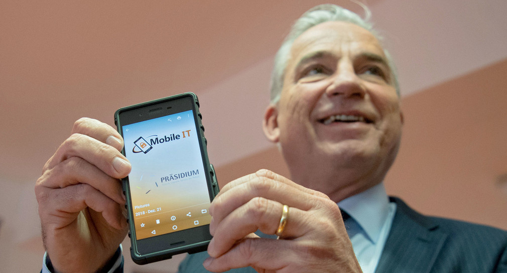 Innenminister Thomas Strobl zeigt während einer Pressekonferenz ein Smartphone. (Bild: © dpa)