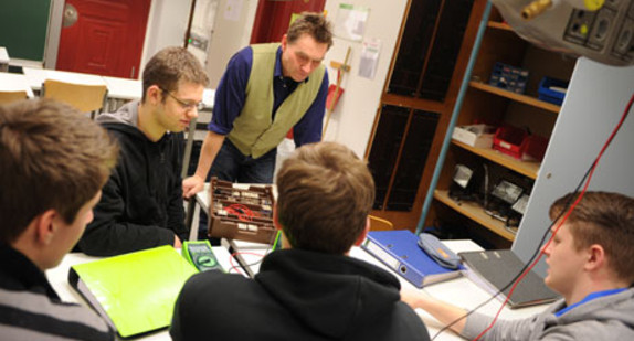 Ein Lehrer erklärt Schülern ein Experiment im Physikunterricht (Bild: © Ministerium für Kultus, Jugend und Sport BW).