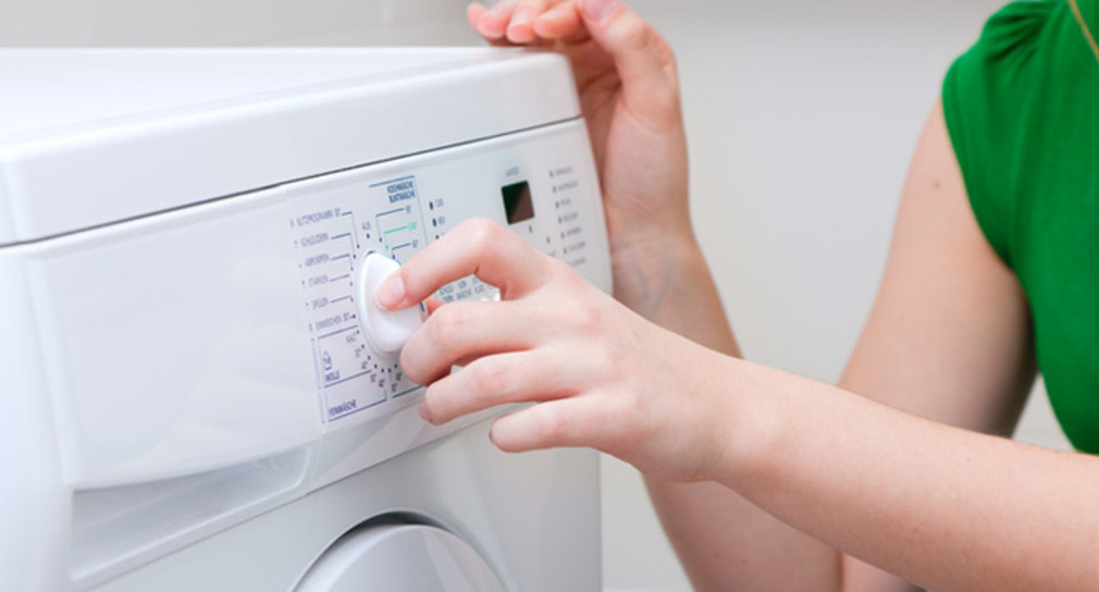 Eine Frau bedient den Drehregler einer Waschmaschine