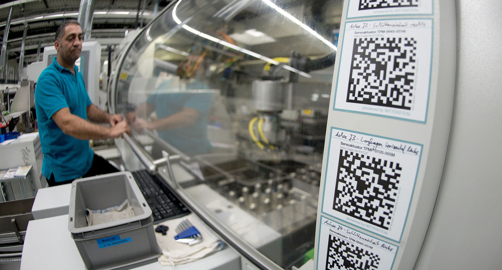 Ein Arbeiter bei der Firma Wittenstein bedient eine Maschine, die mit 2D-Codes ausgestattet ist. (Bild: © dpa)