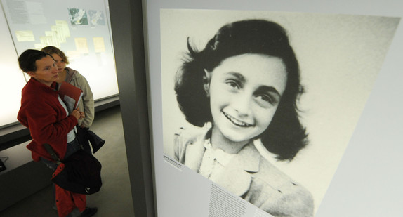 Besucher betrachten in einer Ausstellung ein Bild von Anne Frank (Quelle: dpa).