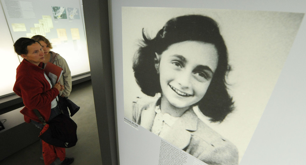 Besucher betrachten in einer Ausstellung ein Bild von Anne Frank (Quelle: dpa).