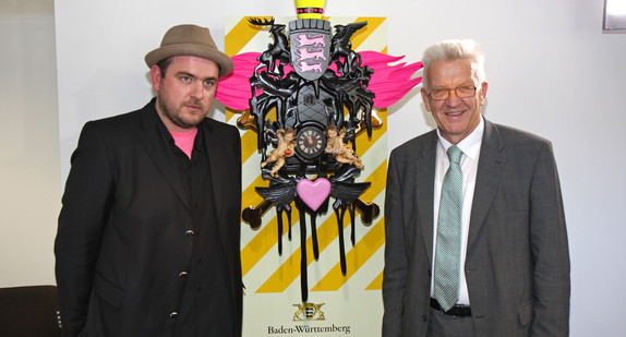 Der Künstler Stefan Strumbel (l.) und Ministerpräsident Winfried Kretschmann (r.) mit dem Kunstwerk „Heimat großer Kunst“