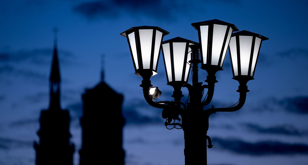 Eine Straßenlaterne leuchtet vor den Türmen der Stiftskirche. 