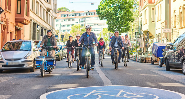 Verkehrsminister Hermann, Amtschef Frieß sowie Mitarbeiterinnen und Mitarbeiter des Landesradeln durch eine Fahrradstraße.
