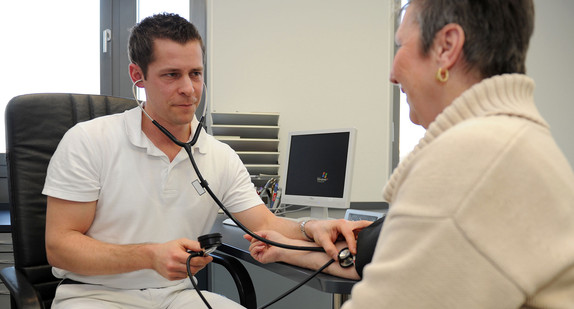 Ein Hausarzt misst den Blutdruck einer Patientin (Bild: © dpa).