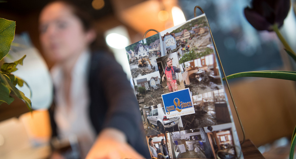 Flyer, die Fotos der Flutkatastrophe in Braunsbach zeigen, stehen im Gasthof Zum Löwen in Braunsbach auf der Theke. (Bild: dpa)