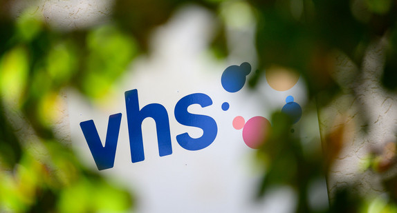 Das Logo der Volkshochschulen (VHS) ist an einem Gebäude angebracht. (Bild: © picture alliance/Sebastian Gollnow/dpa)