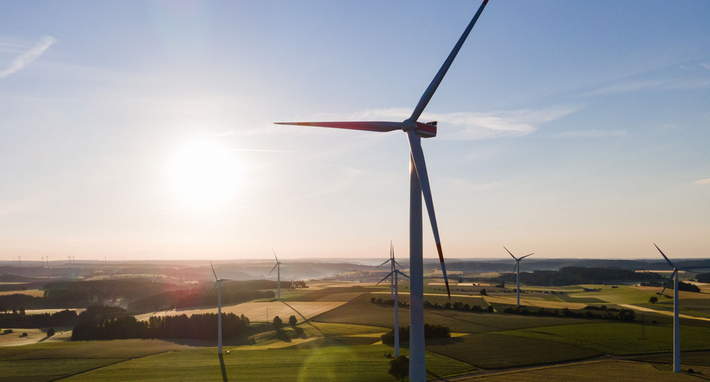 Windräder stehen während des Sonnenaufgangs auf einem Feld.