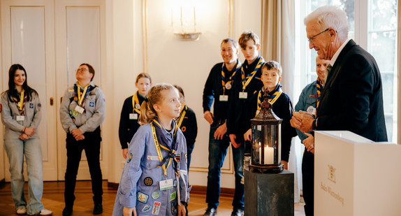 Ministerpräsident Winfried Kretschmann (rechts) mit Pfadfinderinnen und Pfadfindern bei der Übergabe des Friedenslichts