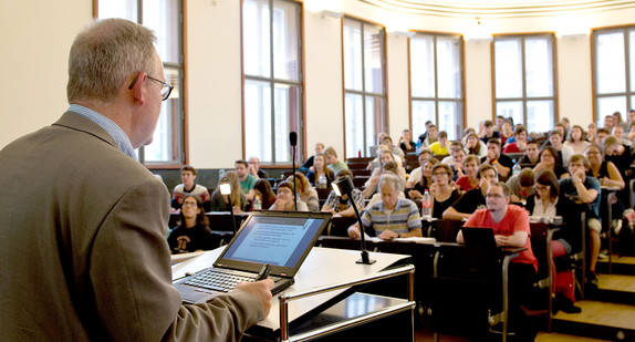 Ein Professor hält in einem Hörsaal vor Studierenden eine Vorlesung.