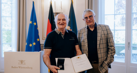 Kunststaatssekretär Arne Braun (rechts) und Erich Schmeckenbecher (links) mit der Staufermedaille und der Verleihungsurkunde.