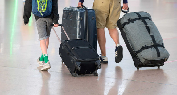 Fluggäste laufen mit ihren Koffern durch ein Flughafenterminal.