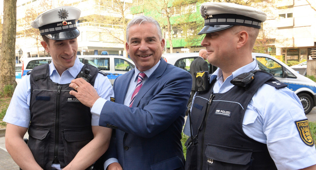 Innenminister Thomas Strobl (M.) betrachtet am 07.04.2017 in Stuttgart zwei mit verschiedenen Body-Cams ausgerüstete Polizisten. (Foto: dpa)