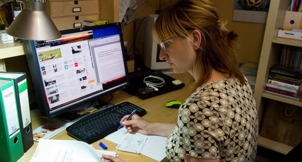 Eine Frau sitzt in ihrem Arbeitszimmer zu Hause und arbeitet am Computer.
