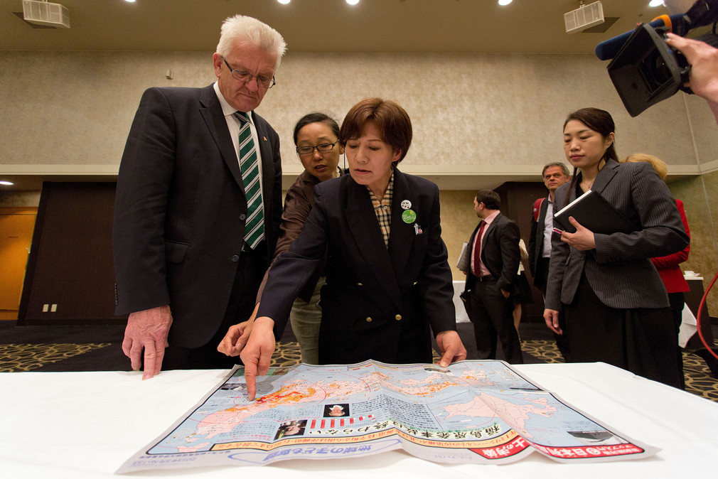 Setsuko Kida (r.), Opfer der Dreifachkatastrophe, erklärt Bundesratspräsident und Ministerpräsident Winfried Kretschmann (l.) im Rahmen einer Gesprächsrunde zur aktuellen Situation in Fukushima auf einer Landkarte das Ausmaß der Verstrahlung.