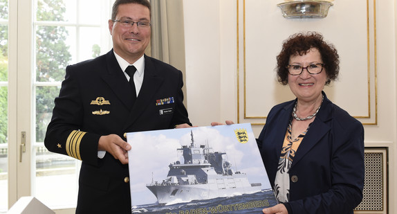 Fregattenkapitän Markus Venker (l.) und Gerlinde Kretschmann (r.) mit einem Foto der Fregatte Baden-Württemberg