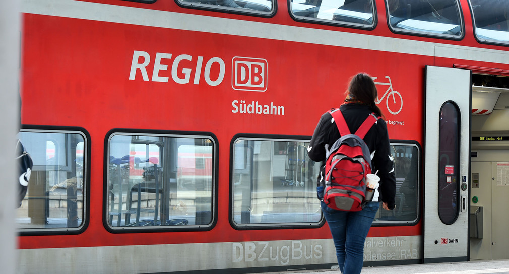 Ein Personenzug „Regio DB Südbahn“ steht in einem Bahnhof.