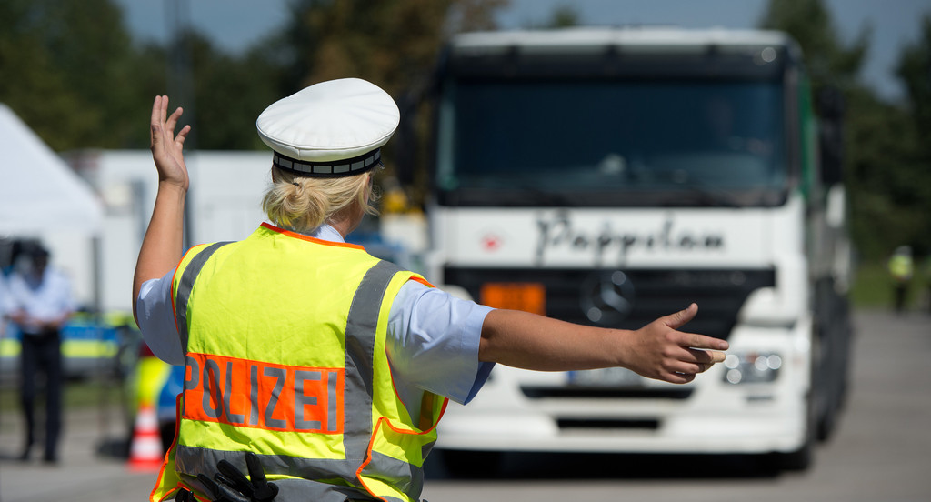 Eine Polizistin weist bei einer Kontrollaktion zum Gewerblichen Güter- und Personenverkehr an der Autobahnraststätte Sindelfinger Wald an der A8 bei Sindelfingen einen LKW ein. (Bild: Marijan Murat / dpa)