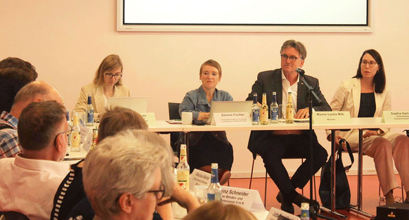 Minister Manne Lucha und die Landes-Beauftragte Simone Fischer sitzen nebeneinander vor den Mitgliedern des Landes-Beirats in einem Konferenzraum.