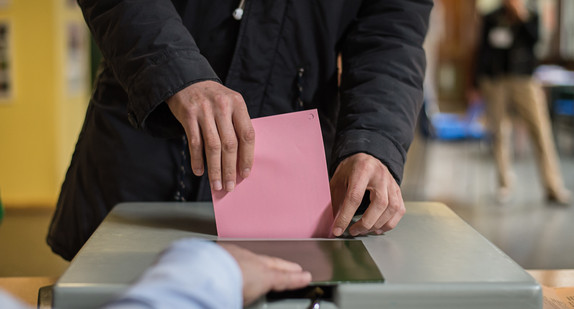 Ein Mann wirft seinen Stimmzettel in die Wahlurne. (Bild: Wolfram Kastl / dpa)