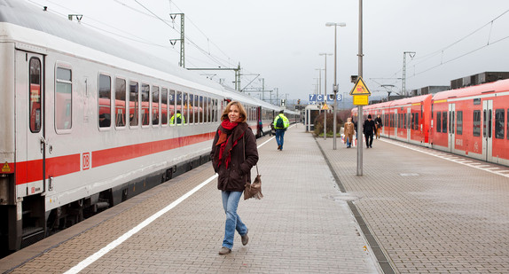 Eine Frau steht auf dem Bahnsteig vor einem Zug