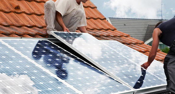 Handwerker verlegen Solarmodule auf einem Dach