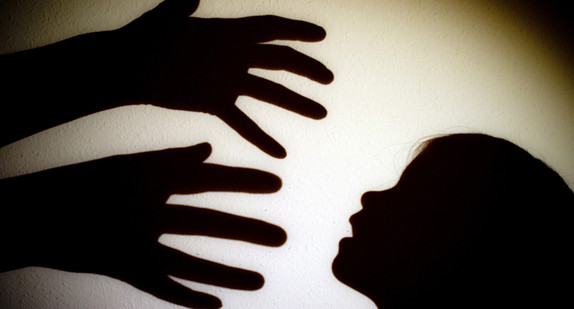 Symbolbild: Schatten von Händen einer erwachsenen Person und dem Kopf eines Kindes sind an einer Wand eines Zimmers zu sehen. (Bild: dpa)