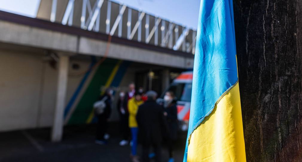 Eine ukrainische Flagge hängt vor dem Eingang eines Gebäudes.