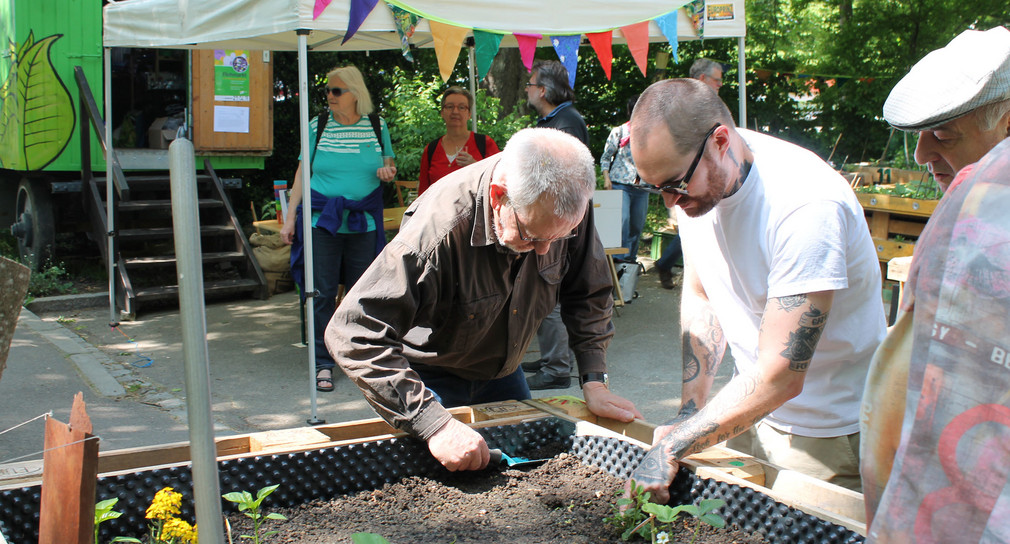 Ein Quartiersgärtner beim Hegen und Pflegen einer selbstgebauten Hochbeet-Kiste im Quartiersgarten im Sanierungsgebiet Dichterviertel in Ulm